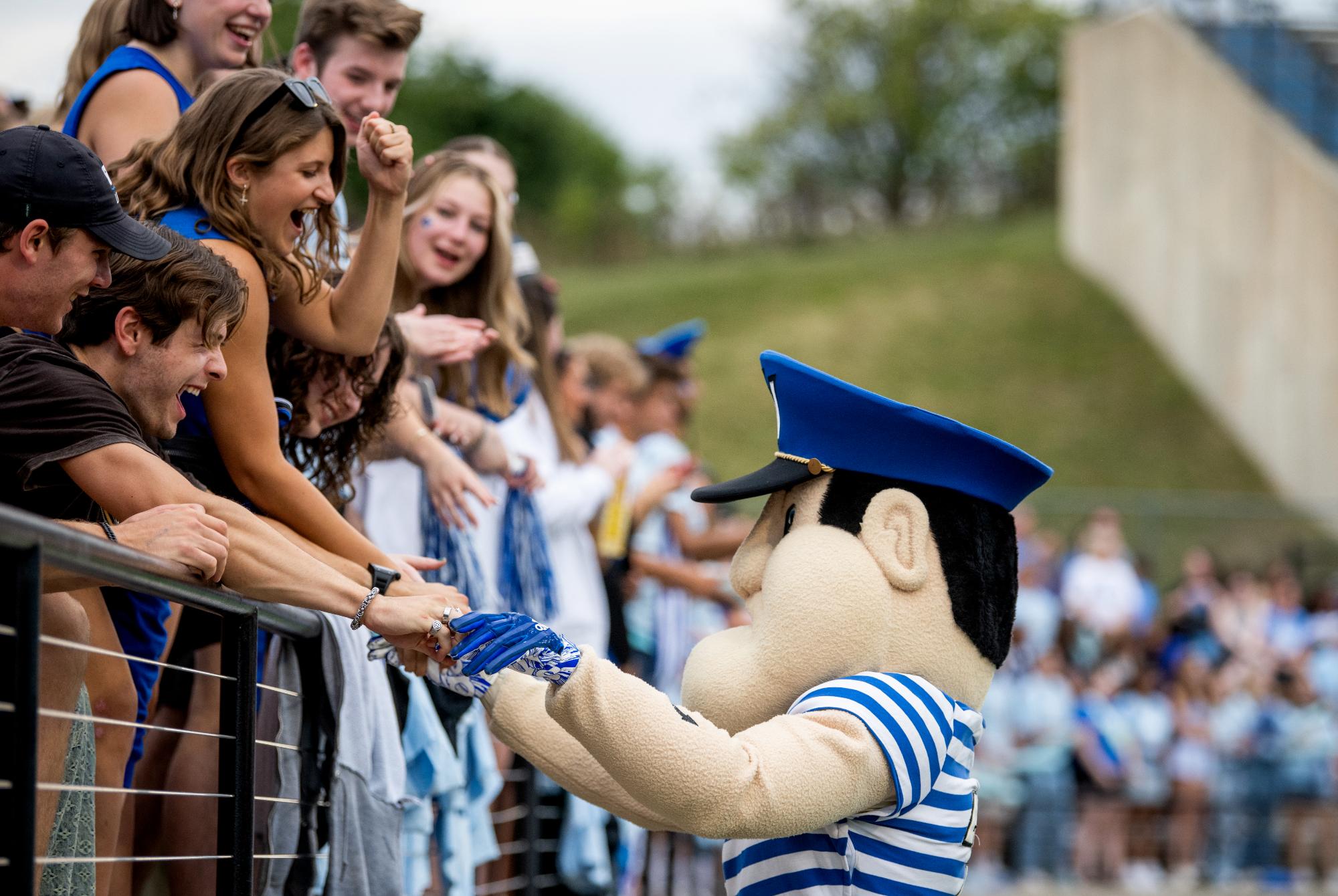 Louie the Laker interacting with GVSU students at a football game.